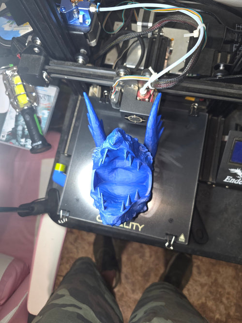 3D printed blue dragon skull pen holder fresh off the printer — top view showing hollow interior